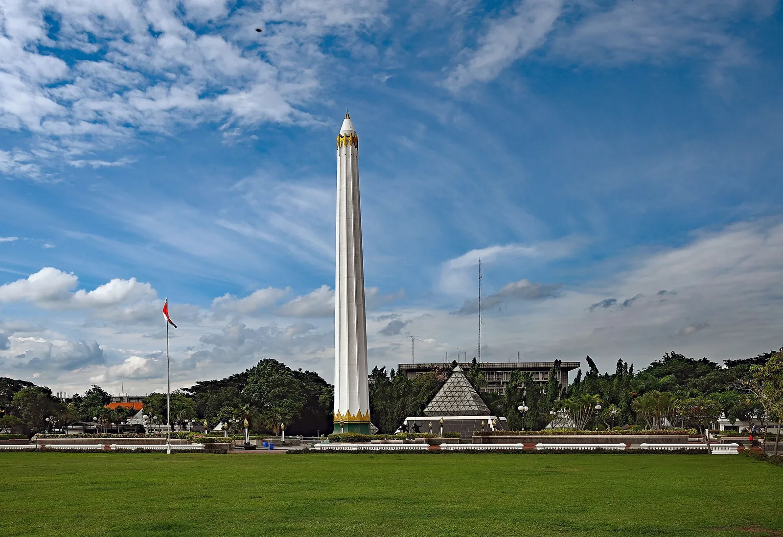 The white Tugu Pahlawan obelisk rising above a wide lawn under a blue sky in Surabaya
