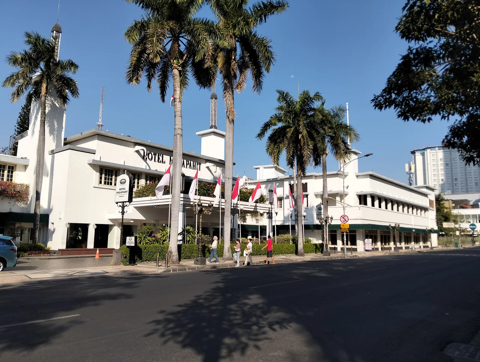The white colonial facade of Hotel Majapahit behind palm trees on Jalan Tunjungan, Surabaya