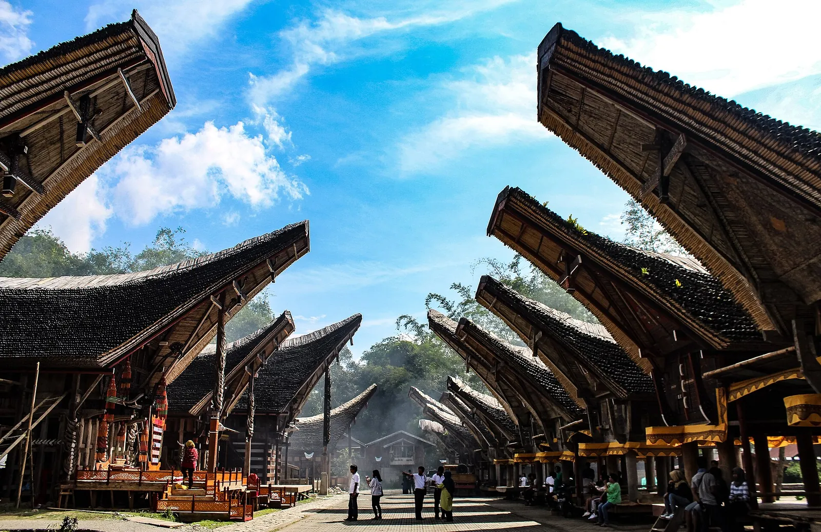 Rows of tongkonan houses with sweeping boat-shaped roofs under a blue sky at Ke'te Kesu', North Toraja