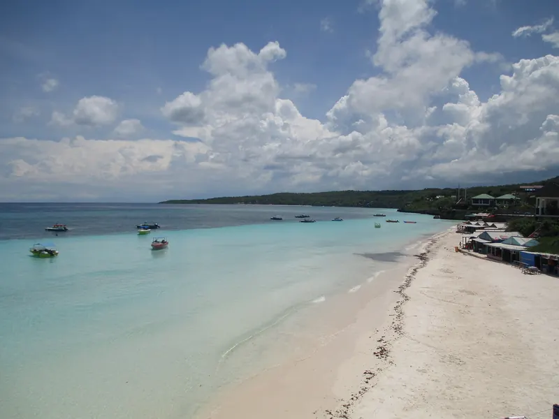 White sand and turquoise water along the main beach at Tanjung Bira, with small boats offshore