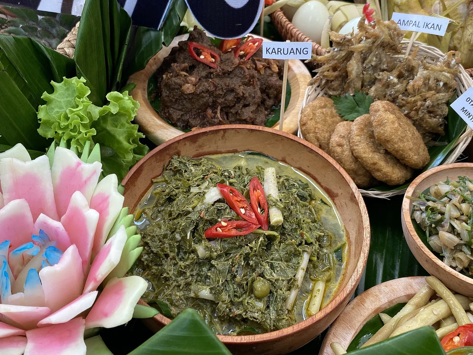 A spread of Dayak dishes from Central Kalimantan with a bowl of kalumpe, pounded cassava leaves topped with red chilli, in the centre
