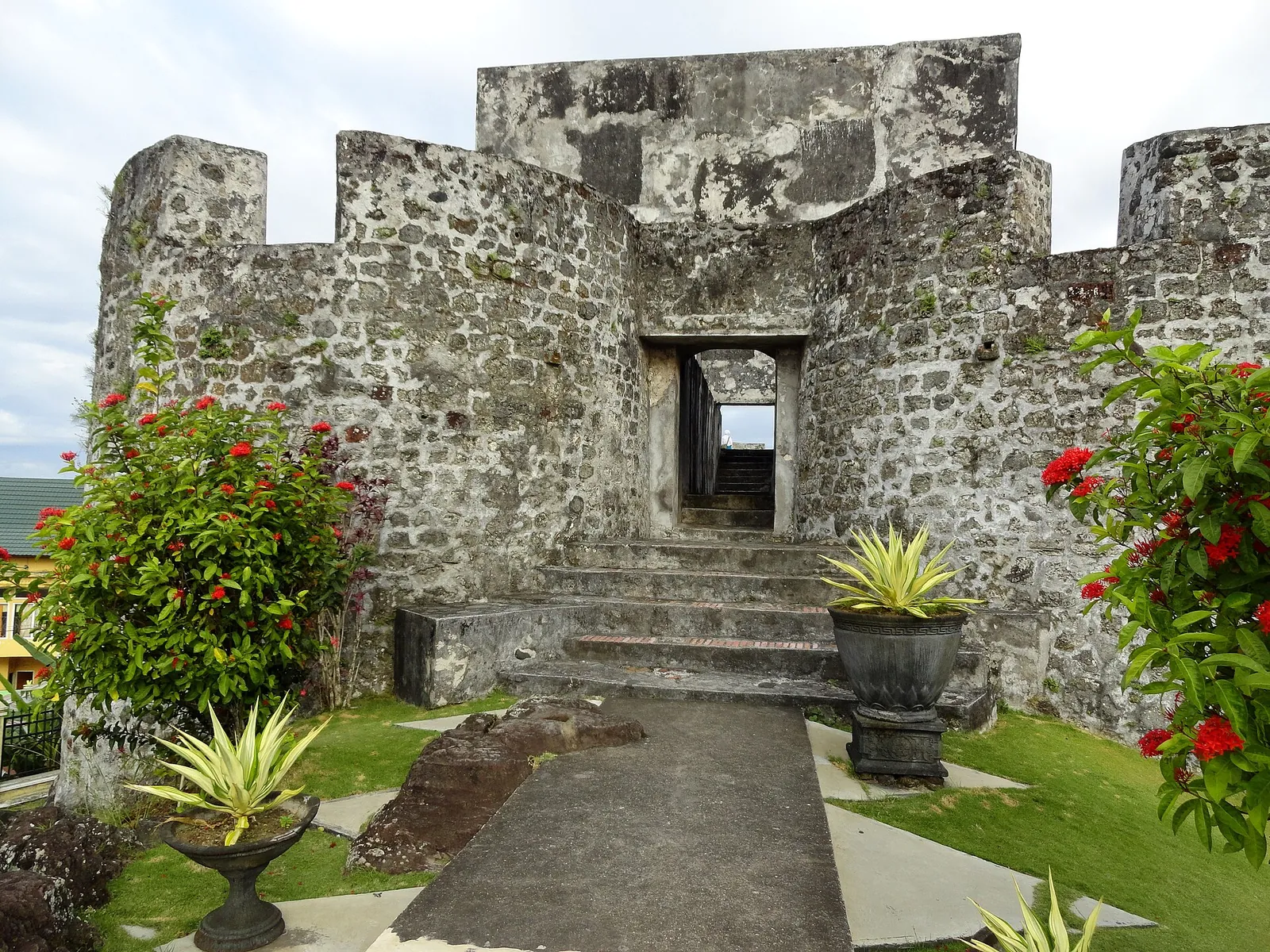 Weathered stone walls and doorway of Fort Tolukko framed by flowers and potted plants