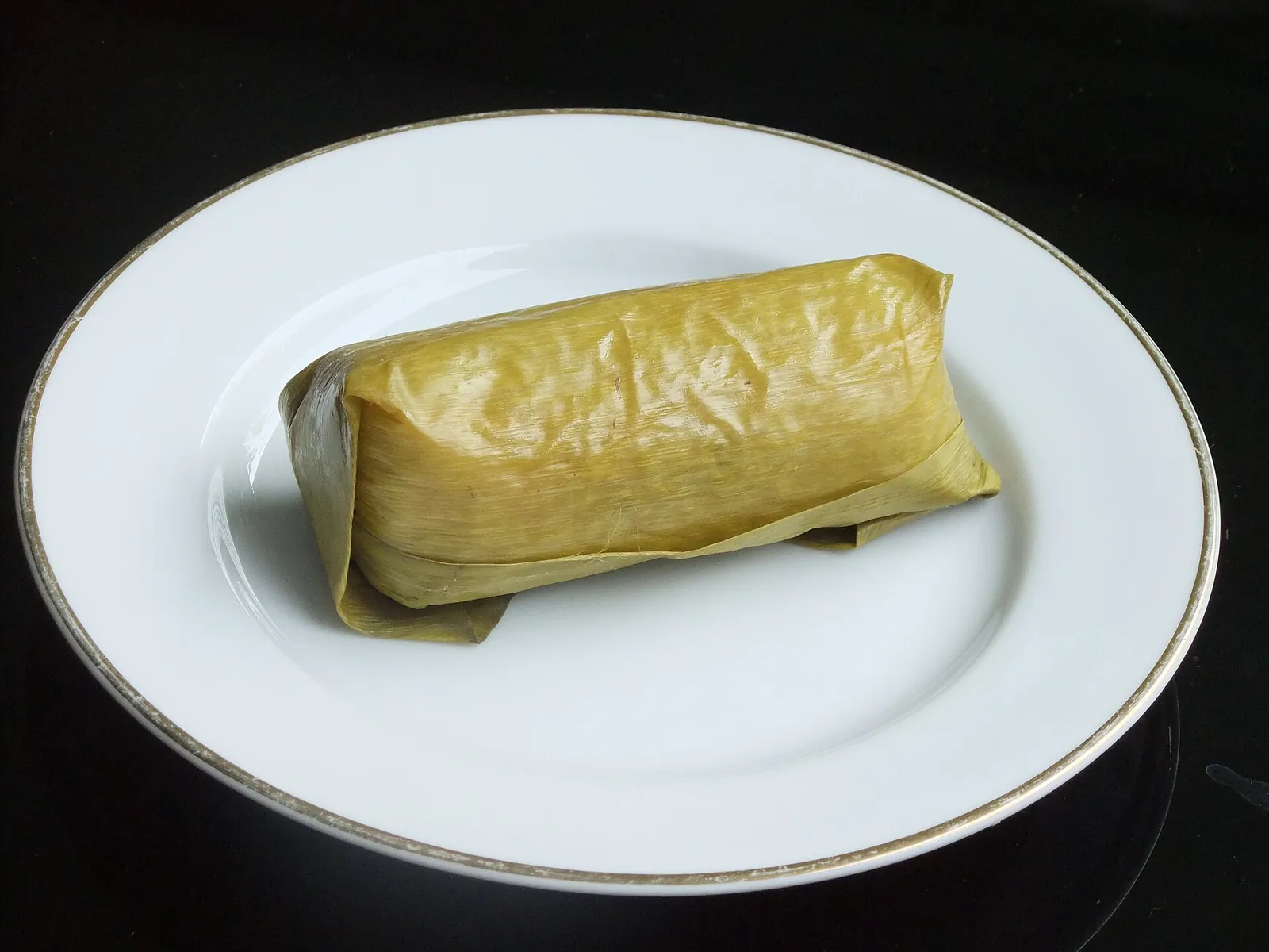 Arem-arem rice roll wrapped in banana leaf on a white plate