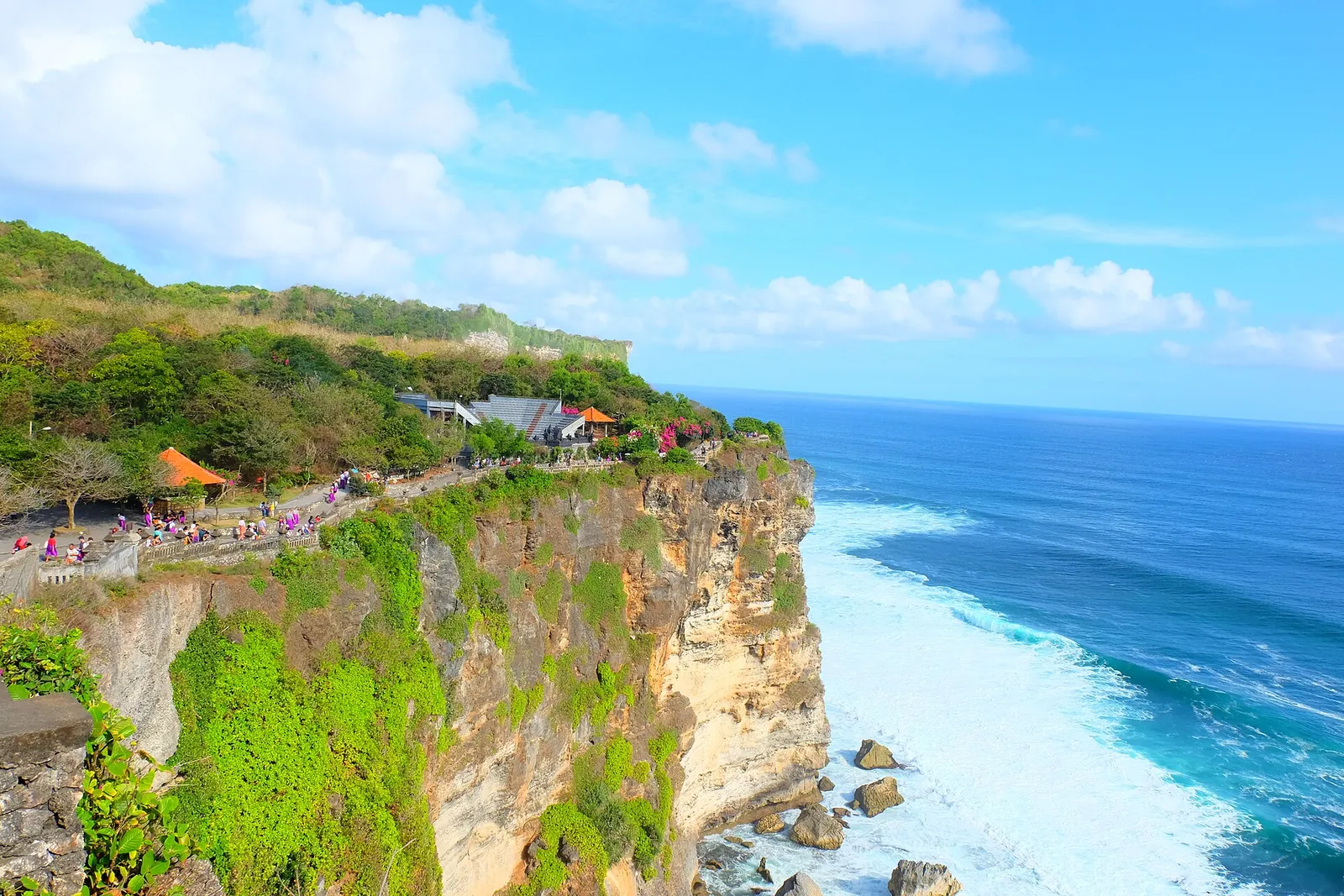 Pura Luhur Uluwatu temple shrines on top of a sheer green cliff above the blue Indian Ocean