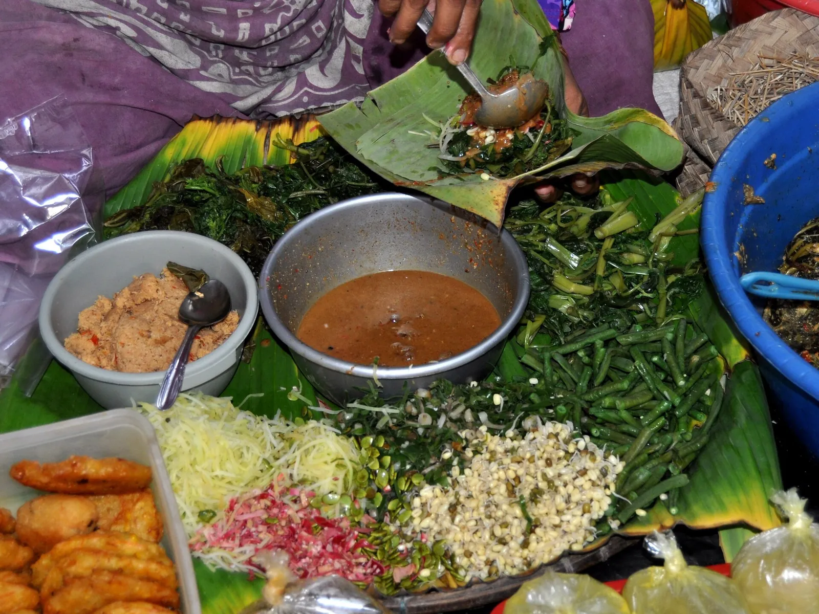 Pecel from Banyumas served on banana leaves: boiled vegetables and bean sprouts with bowls of peanut sauce and fried tempeh