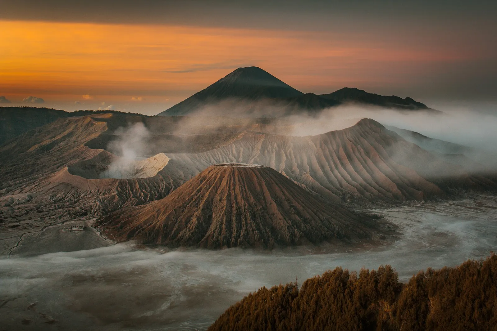 Mount Bromo and its neighbouring cones rising from morning mist in the Tengger caldera, with Mount Semeru behind