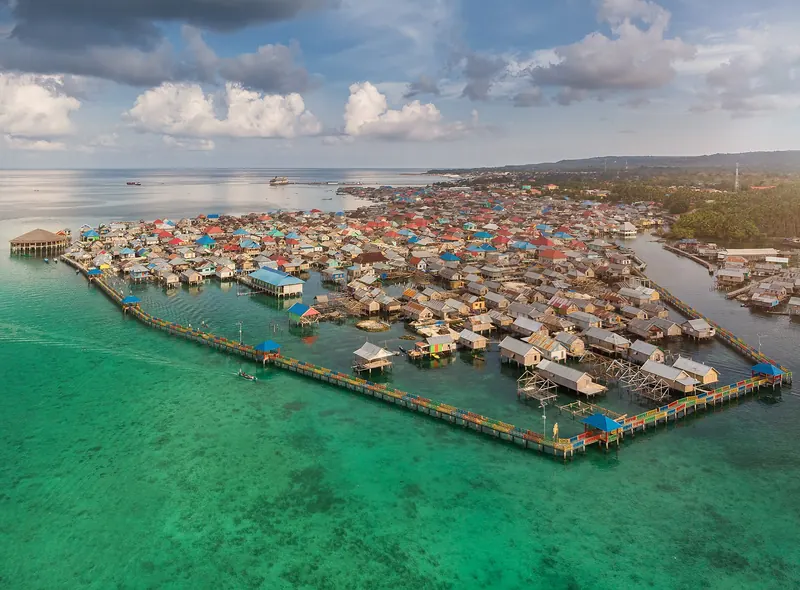 Luftfoto af en bajopælelandsby over turkis lavt vand på Wangi-Wangi i Wakatobi