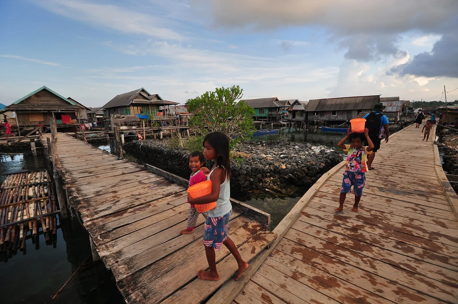 Children walking on a wooden boardwalk between stilt houses in the Bajo village of Sampela, Kaledupa