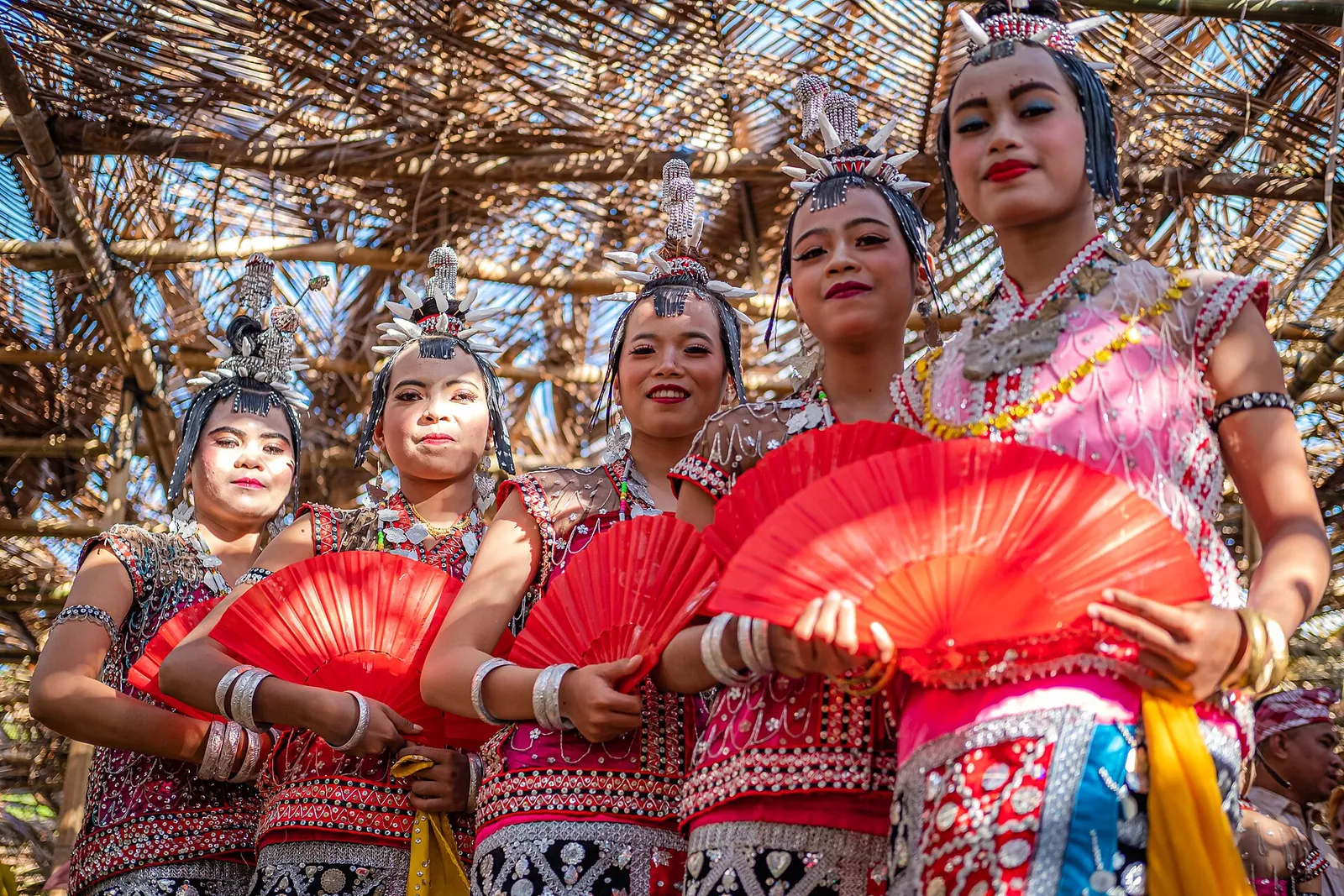 Lariangi dancers in red costumes and ornate headdresses at a festival in Kaledupa, Wakatobi