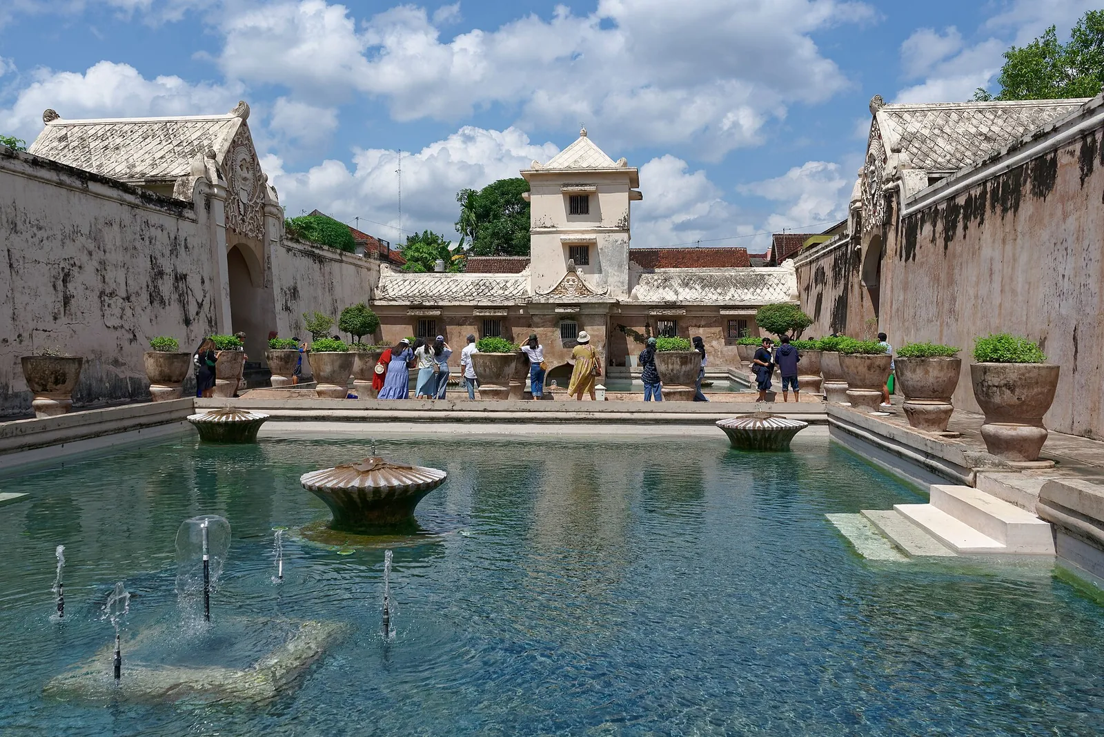 Turquoise bathing pools with fountains and a white tower at Taman Sari Water Castle in Yogyakarta under a blue sky