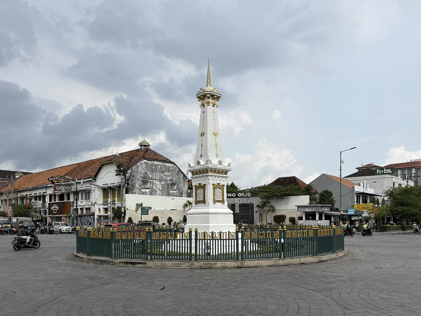 The white and gold Tugu monument on a roundabout in Yogyakarta with colonial-era buildings behind