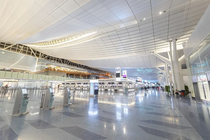 Bright, almost empty departure hall at Haneda Airport Terminal 3 under a high white roof