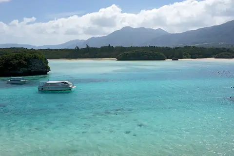 Kabira Bay, en Ishigaki, con aguas turquesa, un barco con fondo de cristal e islotes arbolados bajo un cielo parcialmente nublado