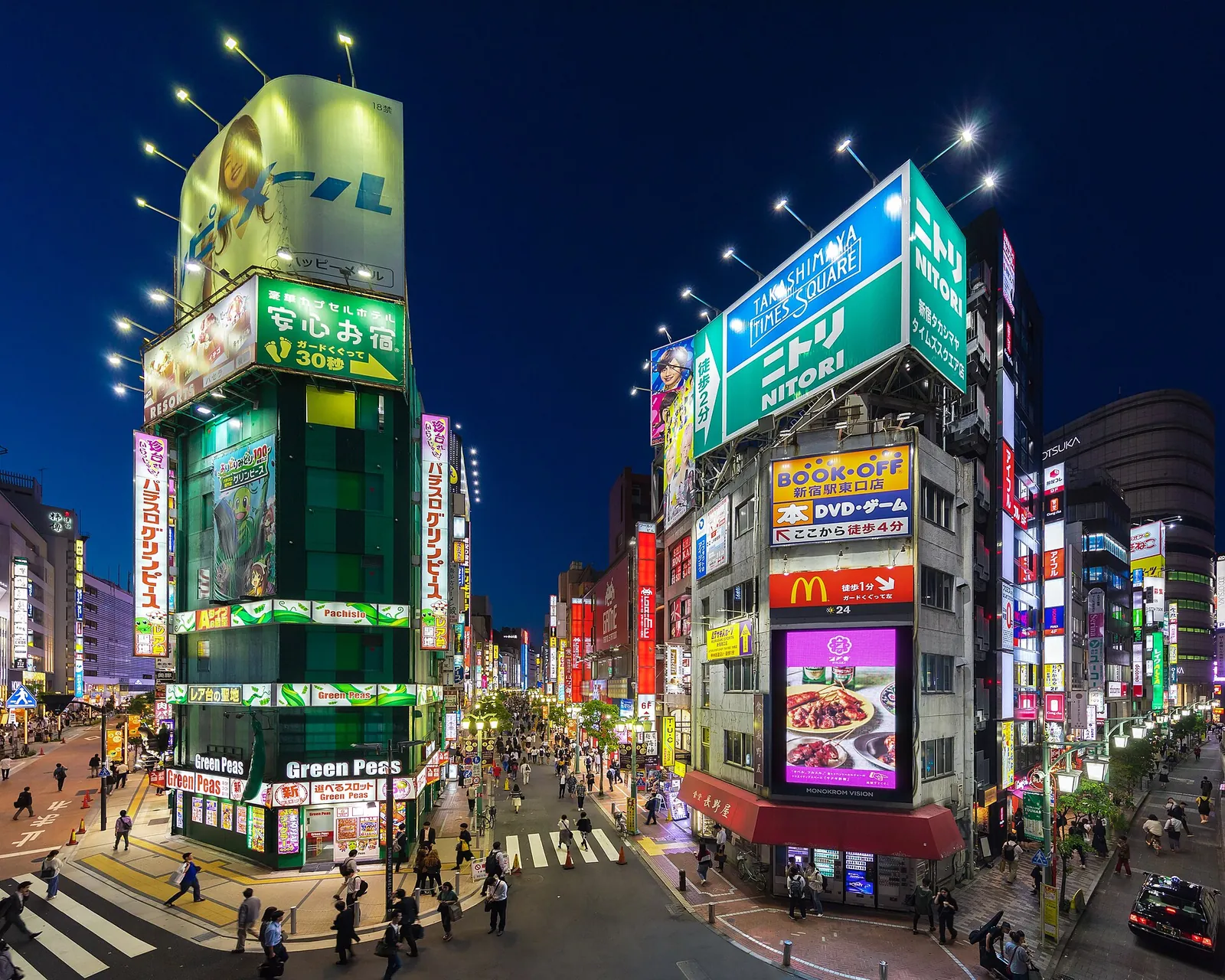 Neonové nápisy a jasně osvětlená průčelí budov na rohu ulice v Shinjuku v modré hodince