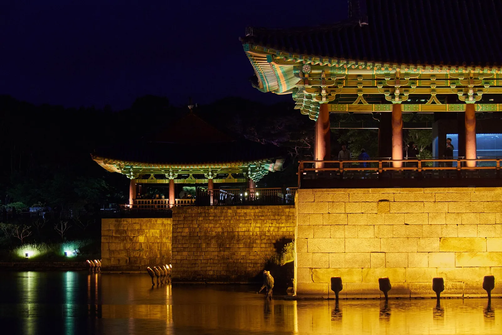 A lit pavilion of Donggung Palace on a stone embankment reflected in Wolji Pond at night