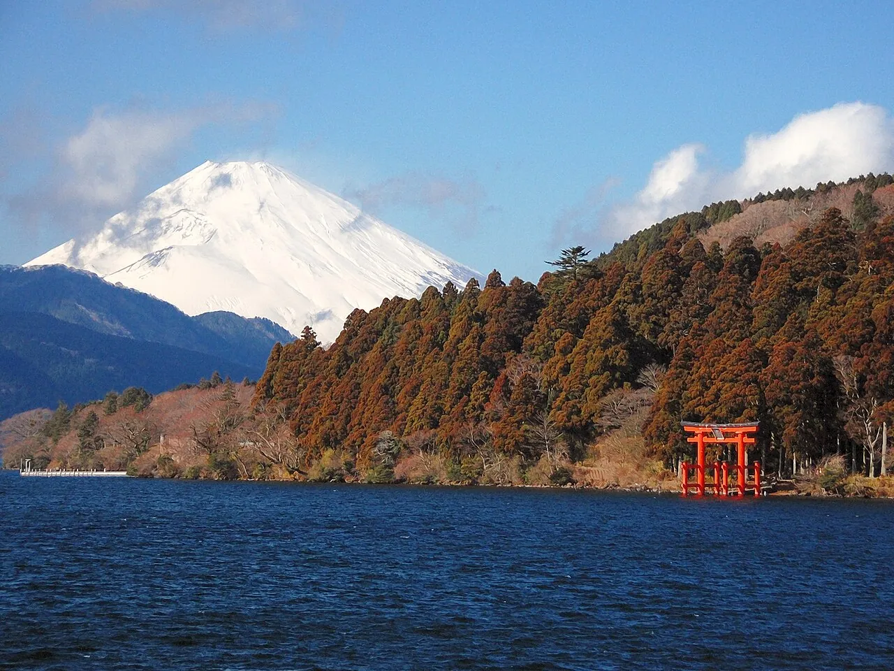 Snow-capped Mount Fuji above Lake Ashi with Hakone Shrine's red torii on the shore