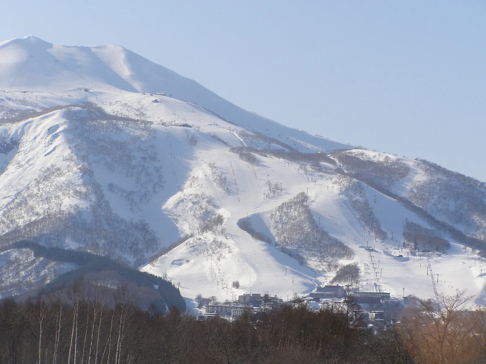 Zasněžené sjezdovky Niseko Annupuri vypínající se nad budovami Hirafu na úpatí hory