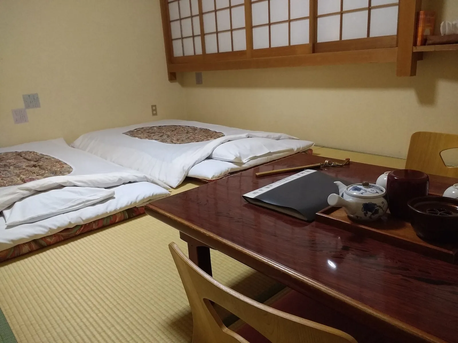 Pokoj s tatami v Ryokan Matsumae v Naře, se dvěma futony rozloženými na podlaze vedle nízkého lakovaného stolku a čajové soupravy