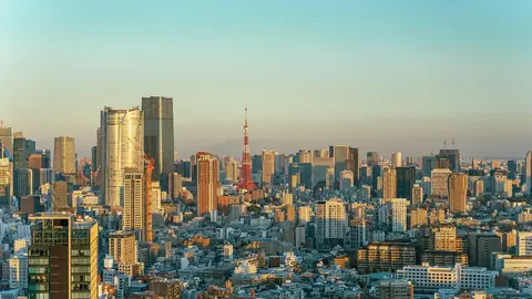 Lumière dorée de fin d'après-midi sur les tours de Minato, avec la Tokyo Tower rouge et blanche au centre de l'horizon