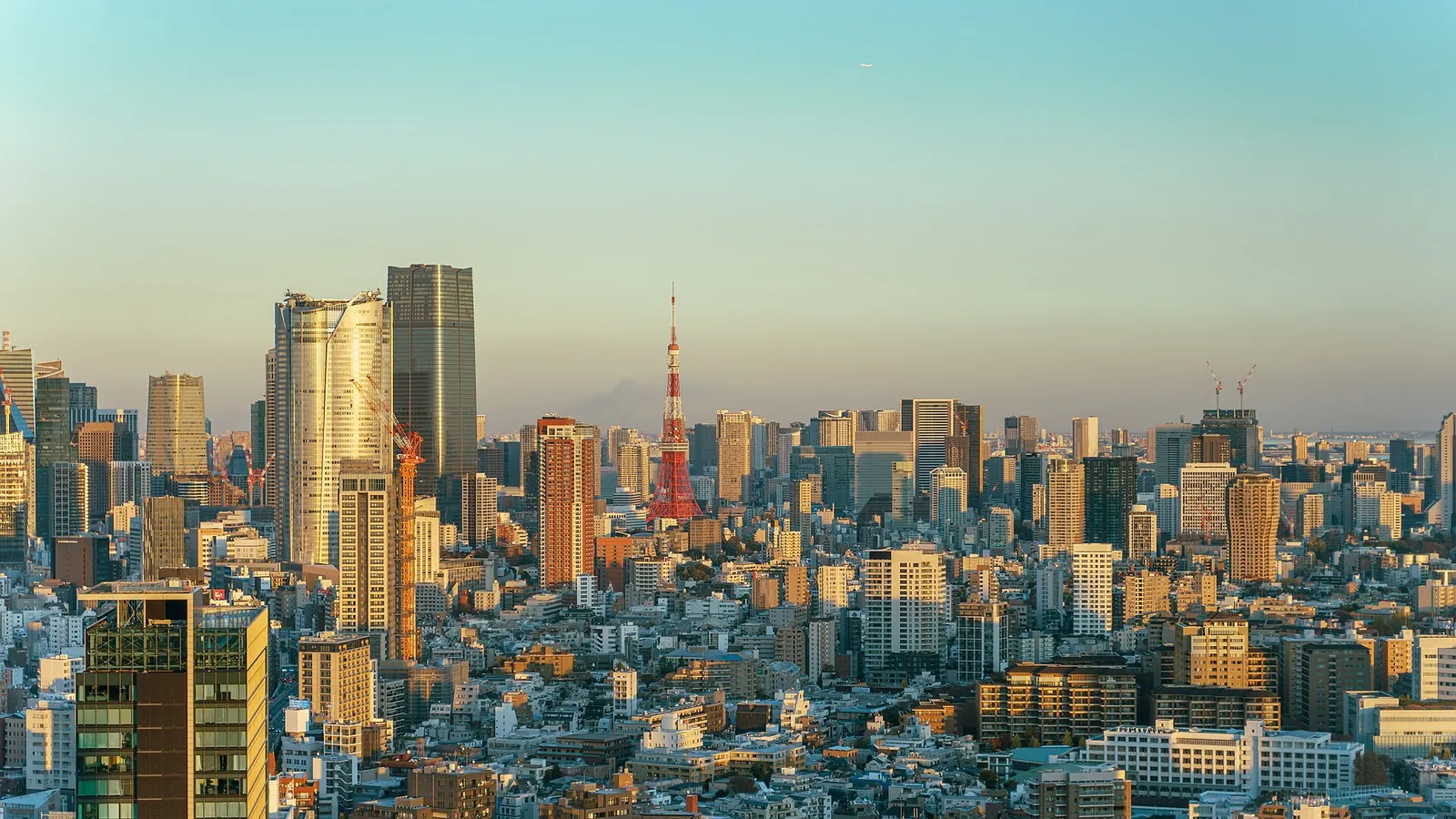 Zlaté pozdně odpolední světlo nad věžemi Minata, s červeno-bílou Tokyo Tower uprostřed panoramatu