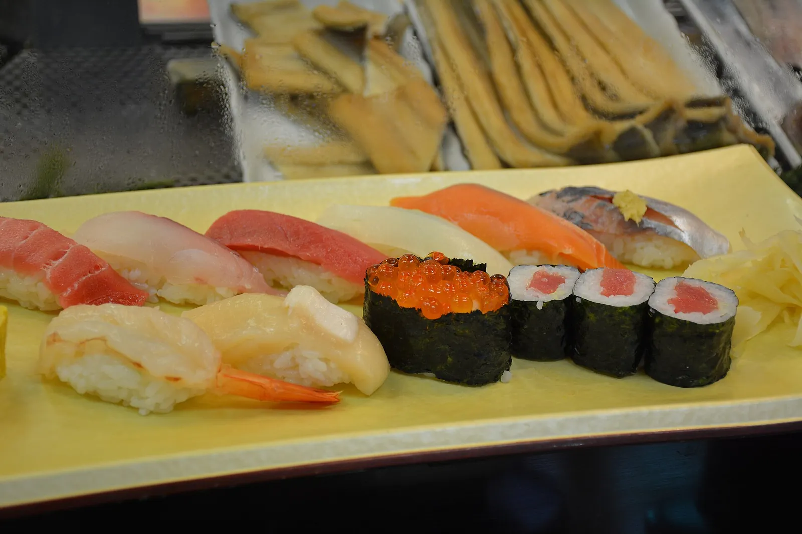 Talíř sushi nigiri a maki s tuňákem, bílou rybou, lososem, krevetou a lososím kaviárem u sushi pultu