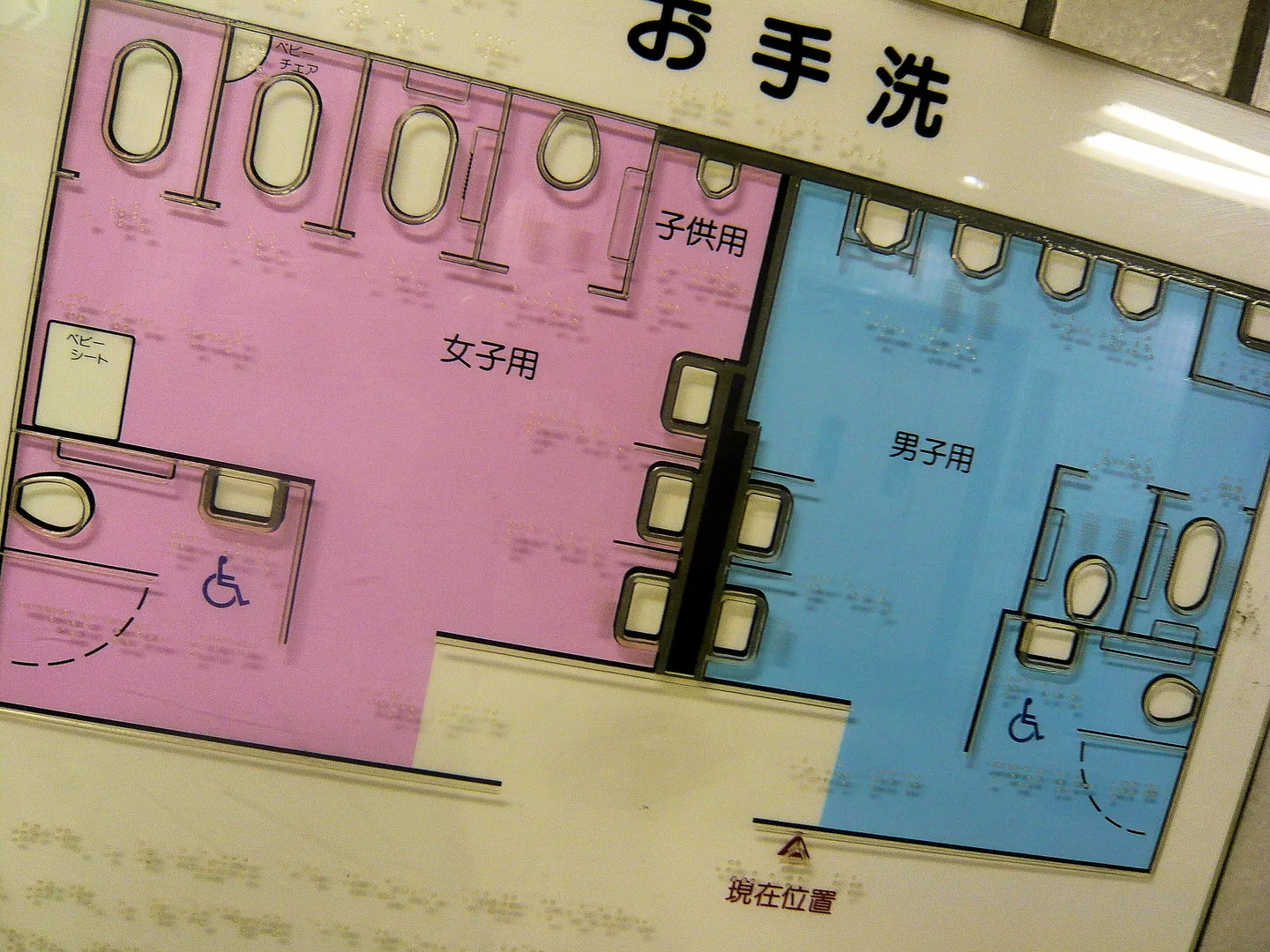 A tactile toilet-layout sign with Braille and coloured symbols in Japan.