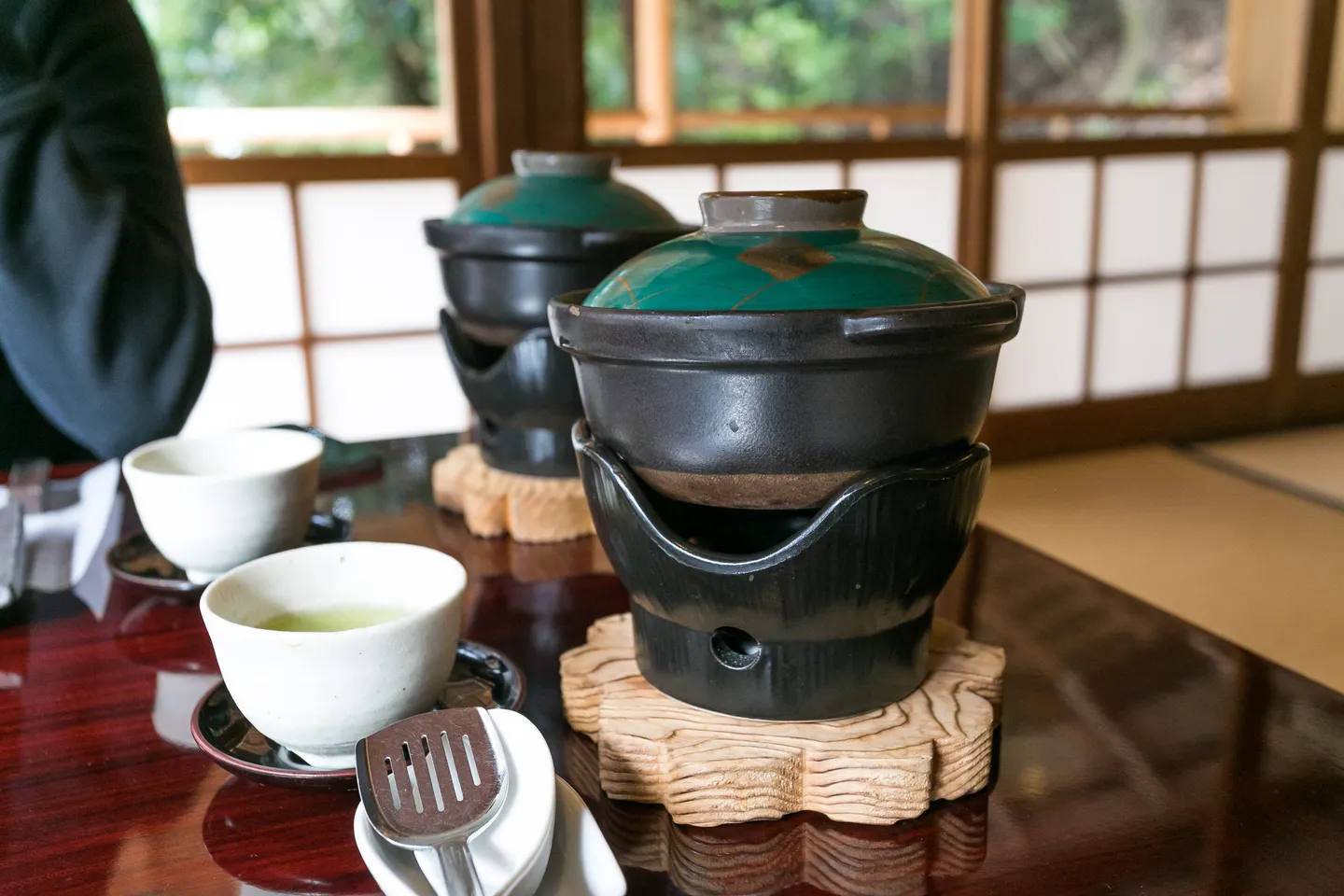 Yudofu serveret i en overdækket gryde med skåle og krydderier i Arashiyama.