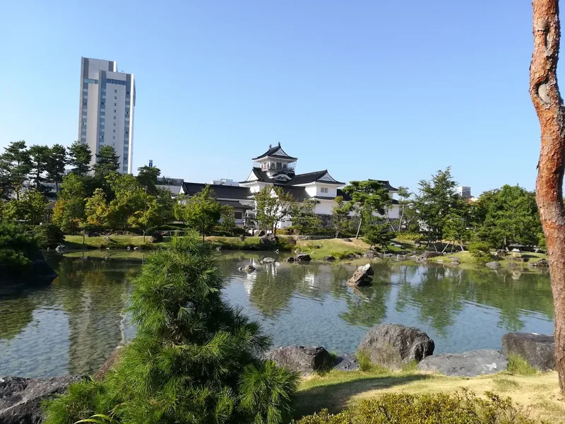 Toyama Castle reflected in the pond in its park.