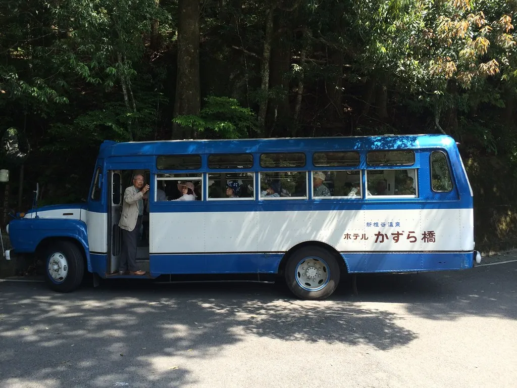 Ein kleiner blau-weißer Bus auf einer Straße im Iya-Tal.