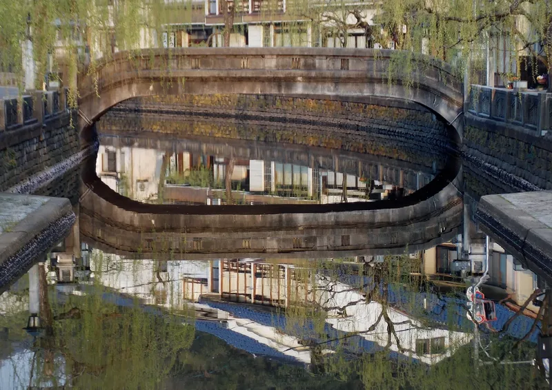 An arched bridge reflected in the canal at Kinosaki Onsen.