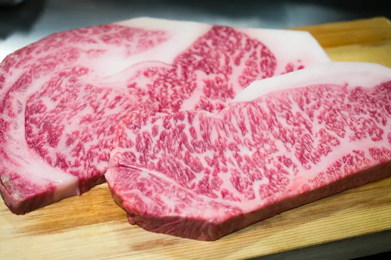 Raw beef with visible marbling on a cutting board, presented by the source as Kobe beef.