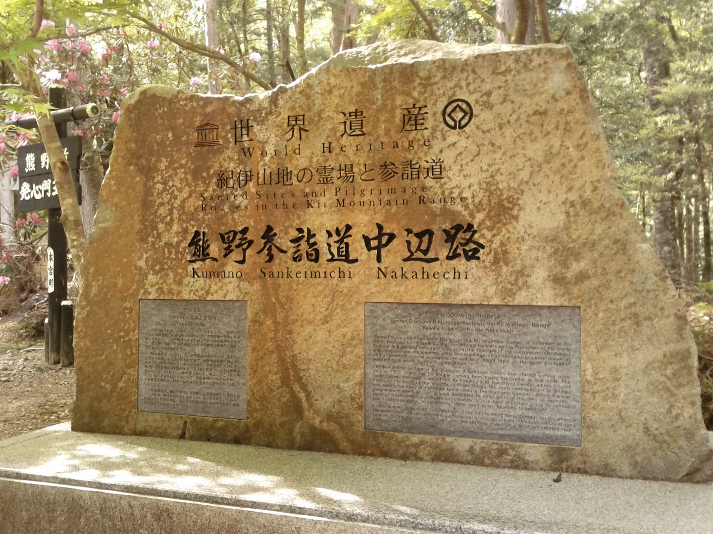 Et steinmonument til Kumano Sankeimichi Nakahechi-ruten blant trær.