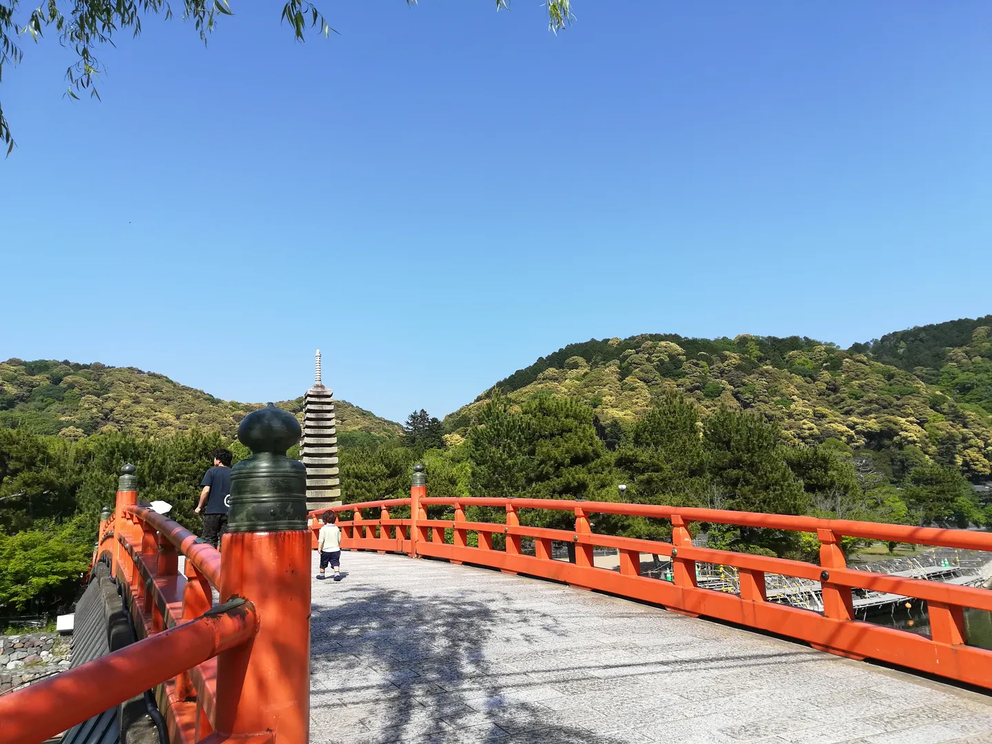 A red bridge over the Uji River with wooded hills beyond.