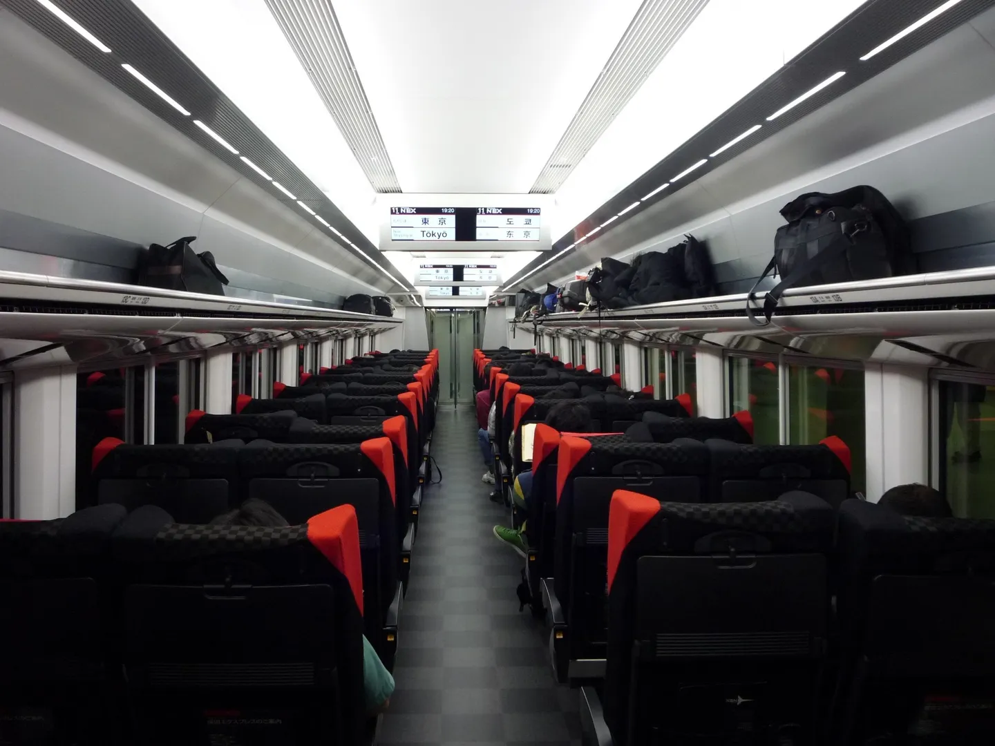 The interior of a Narita Express train with luggage in overhead racks, in an archival photograph.