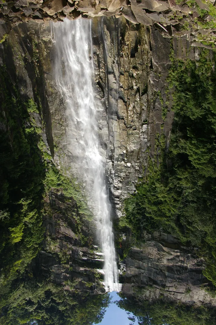 Nachi Falls nedför en klippig klippa omgiven av träd.