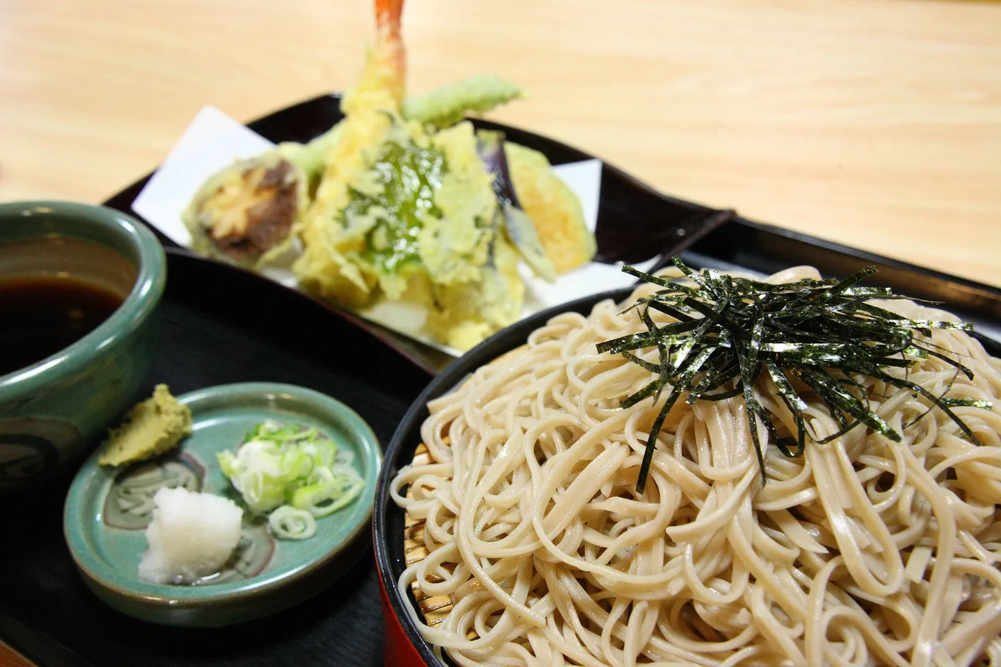 Soba noodles on a tray with tempura and side dishes.