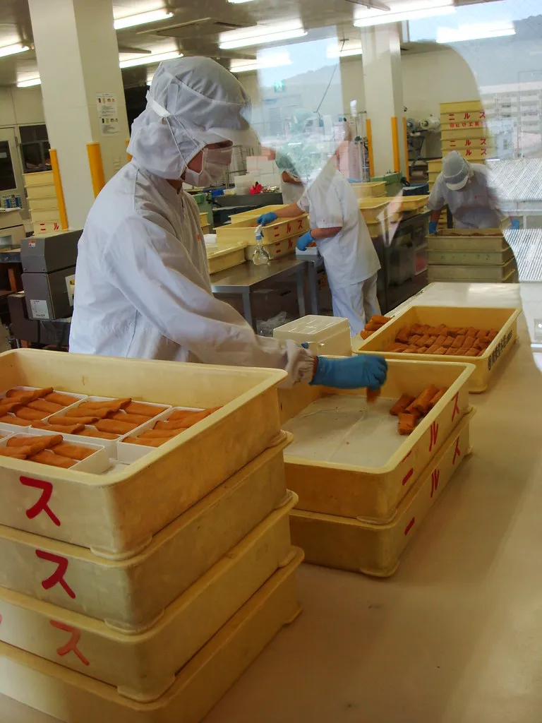 Muncitori pregătind dulciuri kibi dango într-o cameră de producție.
