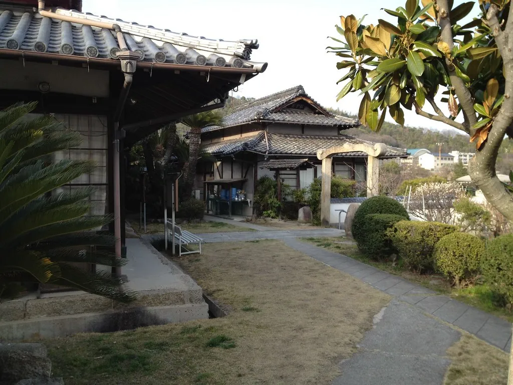 Nádvoří chrámu v Onomichi, s dřevěnými budovami a vegetací.