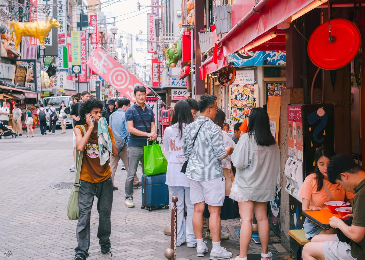 Visitantes en una calle comercial en Dotonbori, Osaka, durante el día.