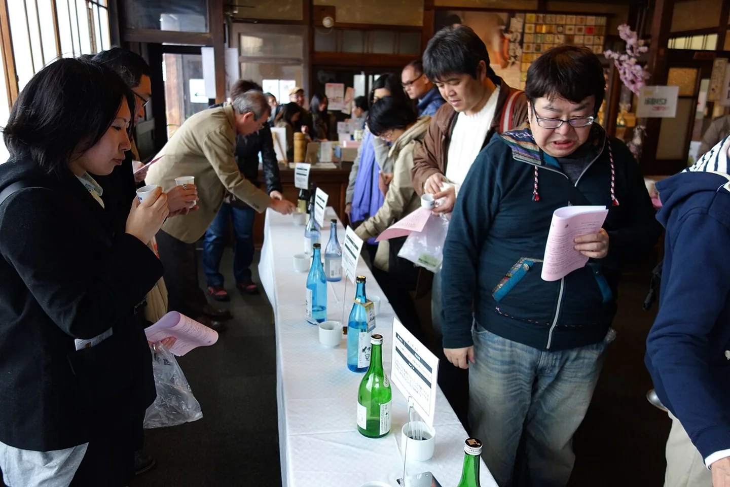Návštěvníci ochutnávají sake na ochutnávce Fushimi
