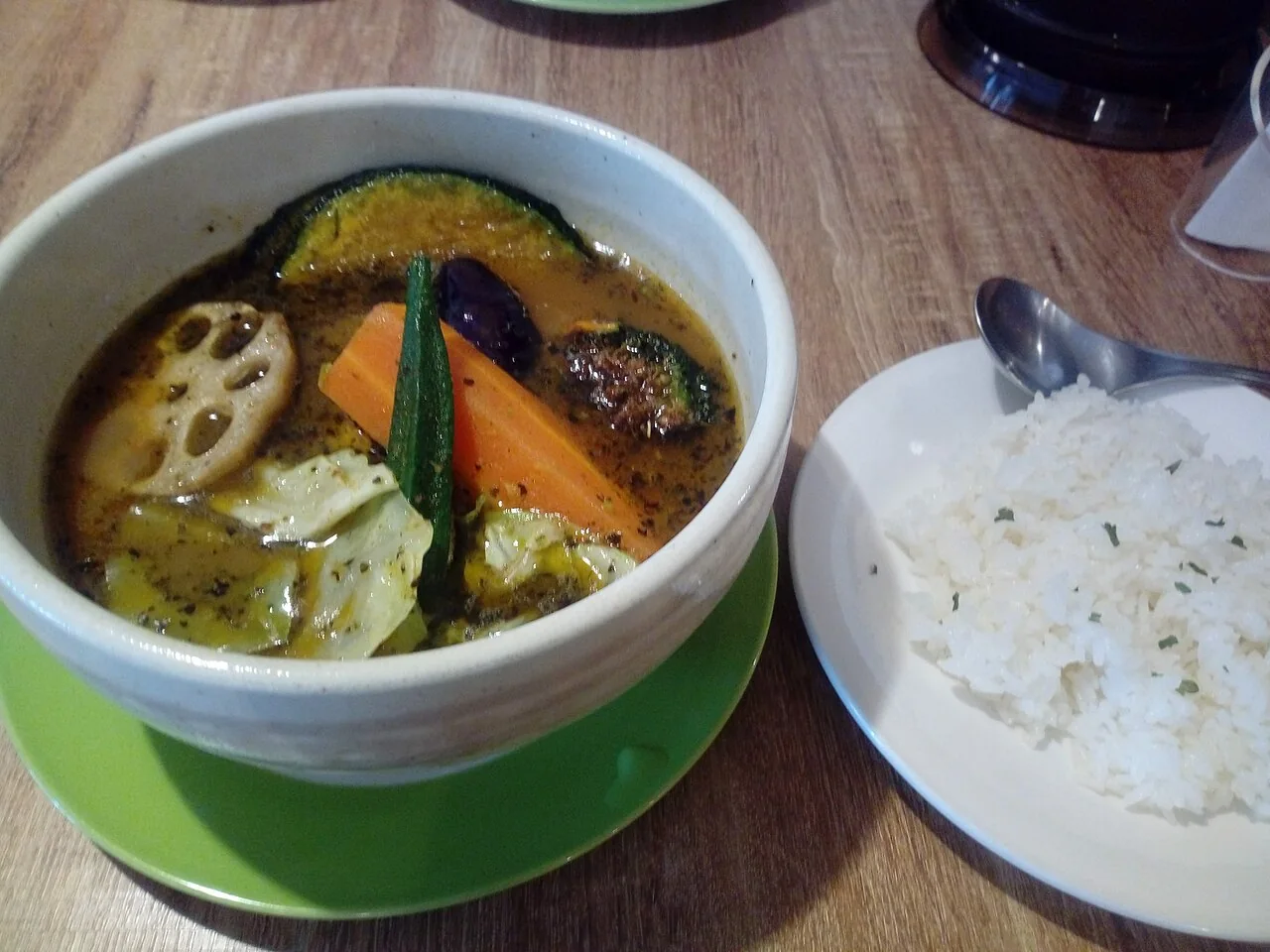Eine Schüssel Suppe Curry mit Lotuswurzel, Karotte, Okra und andere Gemüse, serviert neben weißem Reis in Sapporo.