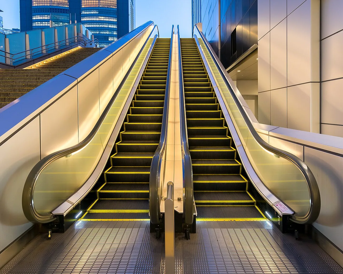 An illuminated outdoor escalator at Shinjuku Station