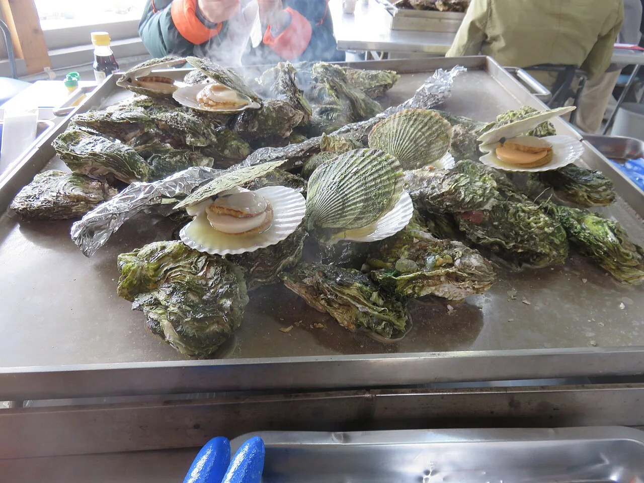 Ostras e vieiras cozinhando numa casa de ostras em Karakuwa, Kesennuma