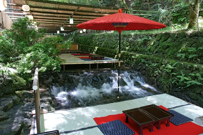 Red parasol and dining tables above the Kibune River in Kyoto.