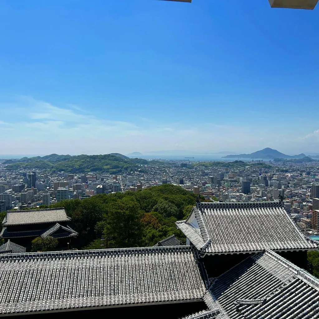 Los tejados del castillo de Matsuyama y la ciudad bajo un cielo azul.