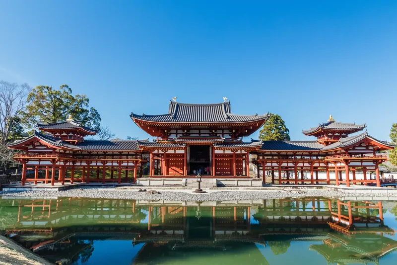 Byodoin's Phoenix Hall reflected in the pond in Uji under a blue sky.