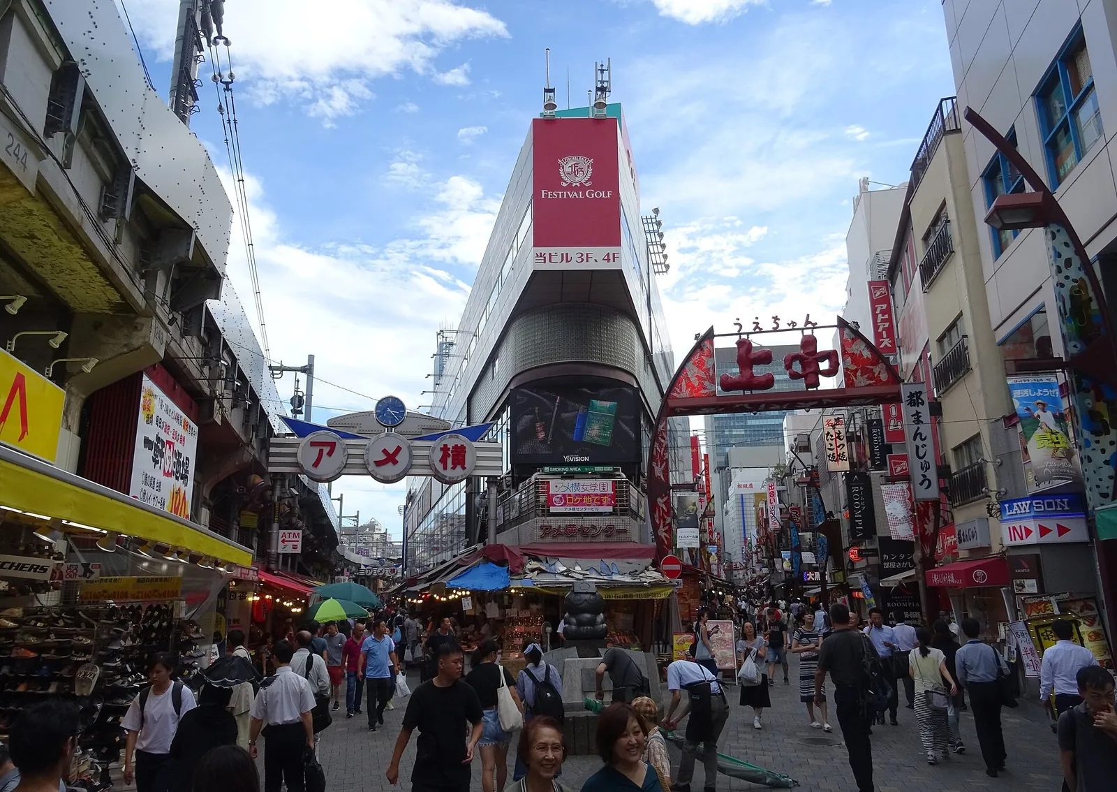 La via dello shopping di Ameyoko a Ueno gremita di acquirenti sotto l'insegna ad arco del mercato, con l'Ameyoko Center Building davanti