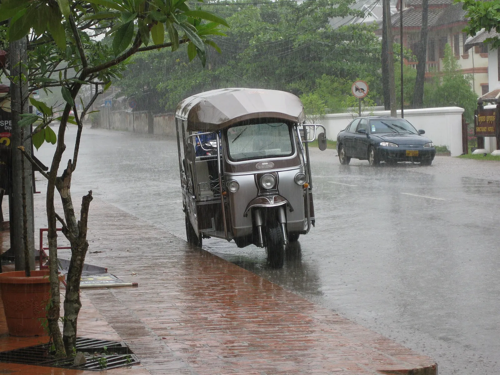 Tuk-tuk na deštěm promáčené ulici v Luang Prabangu