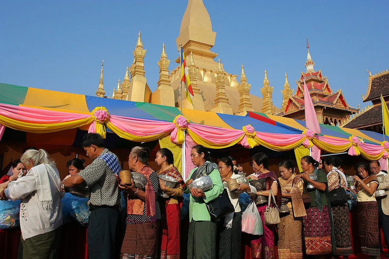Ženy v tradičním oděvu s obětinami před zlatou stúpou Pha That Luang při festivalu That Luang ve Vientiane
