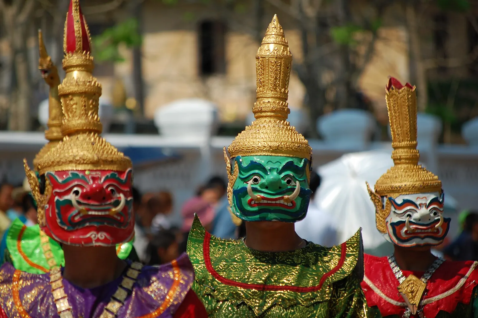 Maskovaní tanečníci se zlatými čelenkami při laoském novém roce